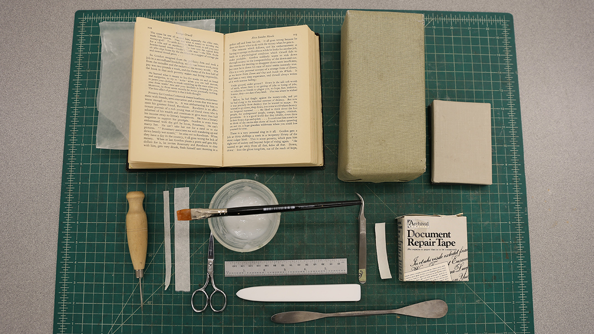 Book and repair supplies laid out on a mat