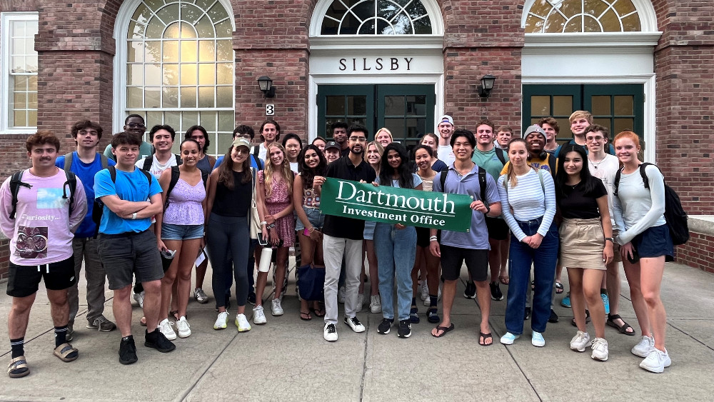 Student interns pose with a Dartmouth banner at the Investment Office.